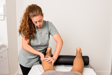 Young professional masseuse doing anti cellulite massage on legs of anonymous patient while working in modern beauty salon