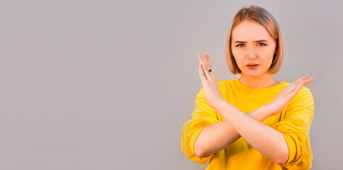 Angry serious european woman showing crossed hands gesture and looking at camera while standing...