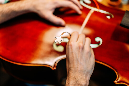 Crop anonymous craftsman setting sound post while building string instrument in workshop