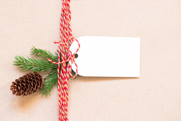 Gift tag and fir branch with cone on brown paper. Christmas and New Year background with copy space