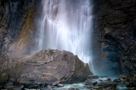 Amazing long exposure view of waterfall falling from steep cliff and splashing against rocky ravine