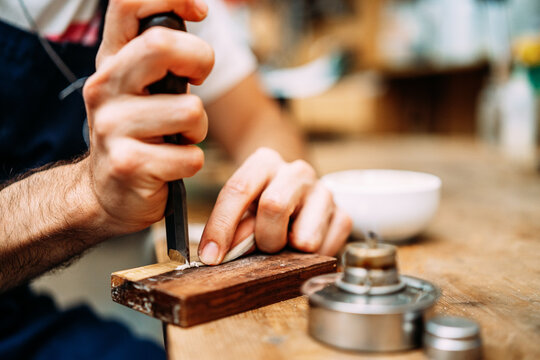 Crop anonymous craftsman using manual cutter while preparing horsehair for violin bow in workshop