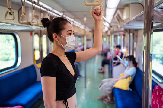 Side view of ethnic female wearing protective mask traveling by train during coronavirus outbreak