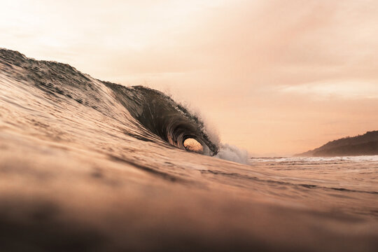 Low angle of powerful tube wave rolling over sea on background of majestic sundown sky in summer