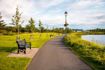 Deserted footpath lined with metal benches in a public park at sunset. Reykjavik, Iceland.