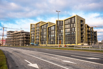 Apartment buildings under construction along an urban road at sunset. Reykjavik, Iceland.