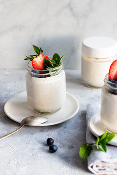 From above homemade cashew vegan yogurt served on glass jars on white rustic table