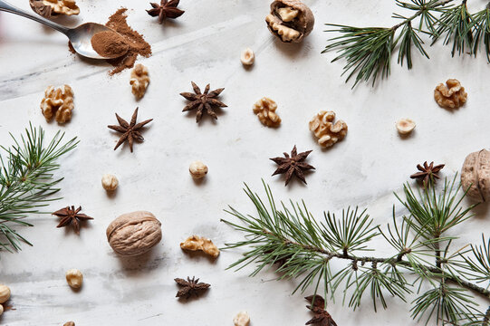 Xmas decoration including natural green fir branches composed with walnuts and aromatic anise stars on white marble surface