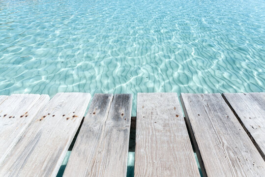 Scenery of old wooden quay over glaring clear sea water on sunny day in Playa de Alcudia