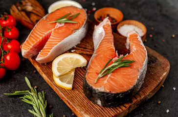  Raw fish salmon steak with lemon and rosemary on a stone background