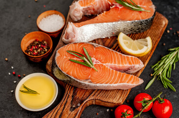  Raw fish salmon steak with lemon and rosemary on a stone background