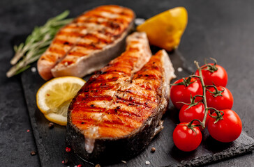 Grilled salmon steak with lemon and rosemary on a stone background	