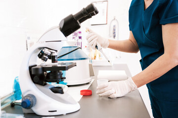 Side view of anonymous person in latex gloves analyzing urine sample while working in laboratory of modern clinic