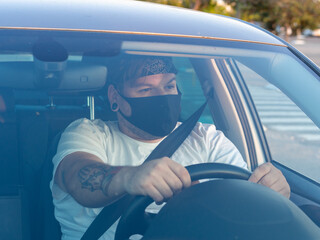 Hombre joven con mascarilla conduciendo respetando las medidas de seguridad de la pandemia del...
