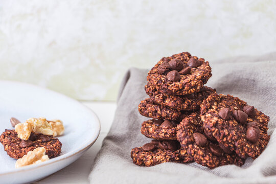 A stack of oatmeal and banana chocolate chips with some wallnuts on a linen cloth