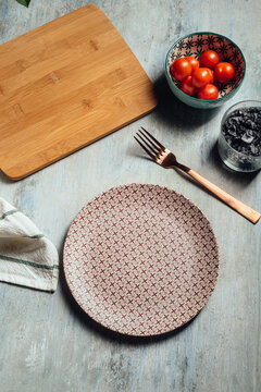Empty plate, Table setting with golden fork, next to a bowl of cherry tomato, table ready for food