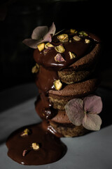 Stack of three chocolate and matcha cupcakes poured with dark chocolate on dark background.