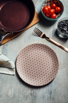 Empty plate, Table setting with golden fork, next to a bowl of cherry tomato, table ready for food