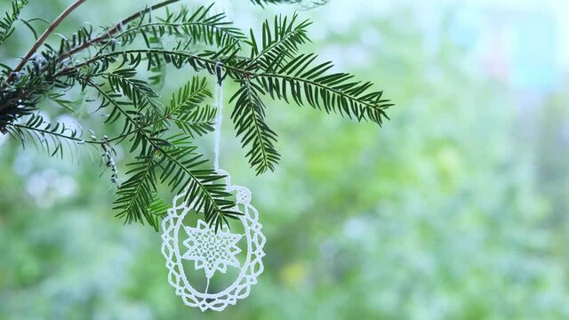 beautiful openwork Christmas tree decoration made of threads, hand weaving, hanging on a coniferous branch, swaying in the wind, concept of Christmas, handmade gift, festive mood