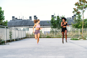 Sportive multi ethnic females in activewear competing with each other while running fast together during training