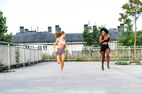 Sportive multi ethnic females in activewear competing with each other while running fast together during training