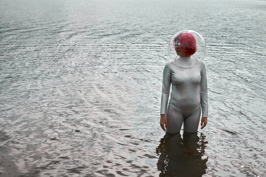 Futuristic young red haired female in silver space suit and glass helmet walking out of flooding river