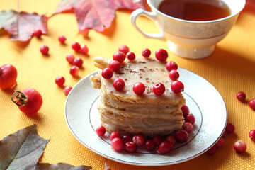 Cranberry berries on a homemade cake on the background of a tea mug, close - up-the concept of a cozy pastime and a delicious tea party on autumn days