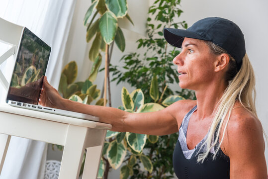 Side view of slim female athlete watching video tutorial on netbook during training at home