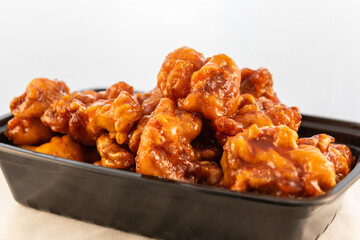 Large bowl of orange flavored chicken shows the sheen of sweet sauce and meat.