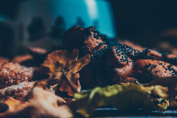 Bun with poppy seeds on an autumn still life with dry oak leaves, warm picture