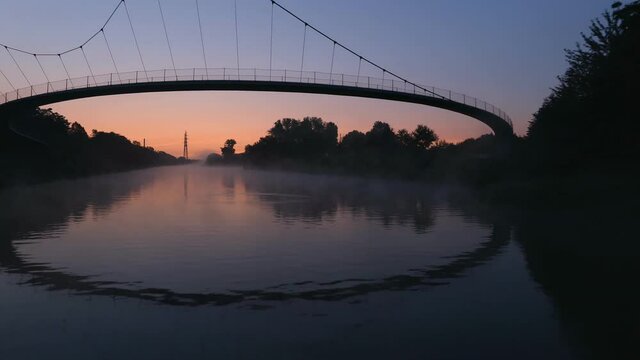 Grimberger Sichel Pedestrian Bridge Over The Rhine-Herne Canal On A Sunset In Gelsenkirchen, Germany. - aerial  - low flying
