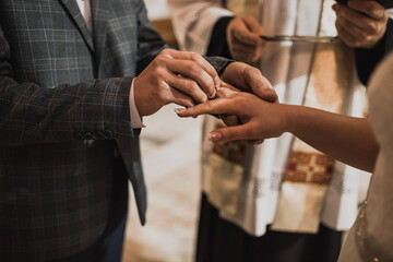 The bride and groom exchange rings. A man puts a wedding ring on a woman's hand. The girl put ring on man.