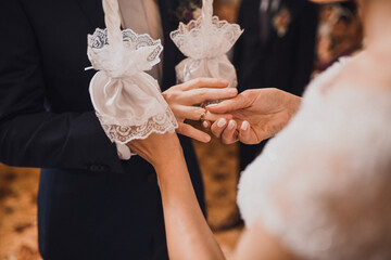 The bride and groom exchange rings. A man puts a wedding ring on a woman's hand. The girl put ring...
