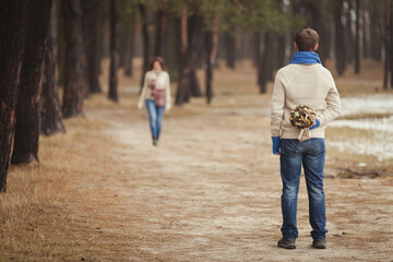 couple on winter walk in snow. Valentine's Day  for couple in rustic style. Happy couple in love warming themselves with tea under a blanket in the arms of nature. Casual outfit with Blue accessories