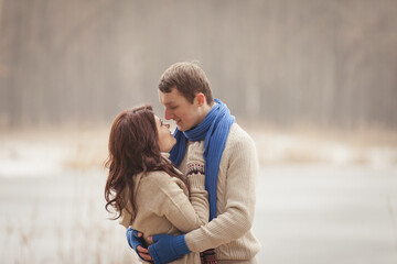 couple on winter walk in snow. Valentine's Day  for couple in rustic style. Happy couple in love warming themselves with tea under a blanket in the arms of nature. Casual outfit with Blue accessories