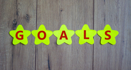 Concept word 'goals' on golden paper stars on a beautiful wooden background. Business concept. Copy space.