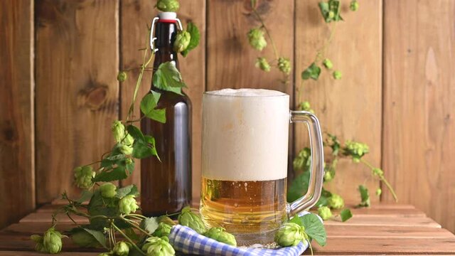 Beer. Cold Craft light Beer in a glass with water drops. Pint of Beer close up on a wooden background. Beer is pouring from the bottle. Border design. High quality 4k footage