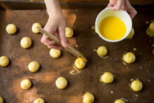Woman hands brushing egg yolk for baking bread