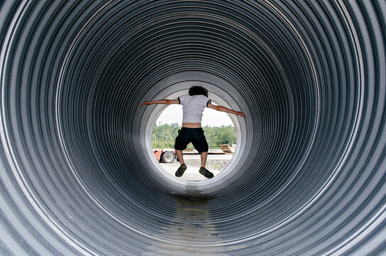Child plays inside a large industrial pipe