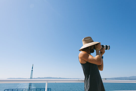 Healthy man taking photo with camera on a ferry boat.