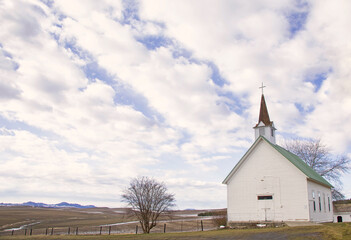 Fototapeta na wymiar Original landscape photograph of a little white country church under a big cloudy sky 