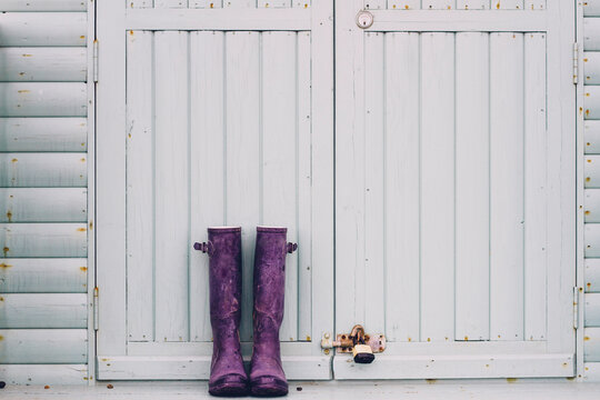 Purple Wellington Boots in front of a beach hut door.