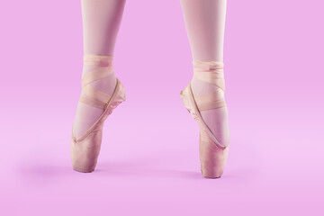 Pies de bailarina de ballet con puntas en fondo rosa 