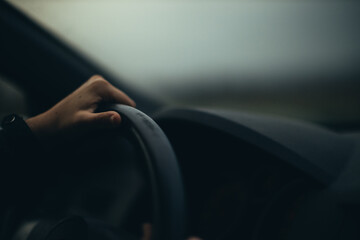 Detail of a woman driving on a long road at dusk.