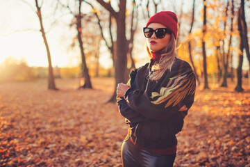 Outdoors lifestyle fashion portrait of beautiful trendy girl walking on the autumn park. Wearing...