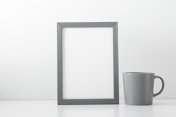 Gray photo frame and cup on white background. Front view, copy space
