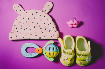 baby set hat, rattle, pacifier and shoes on pink background