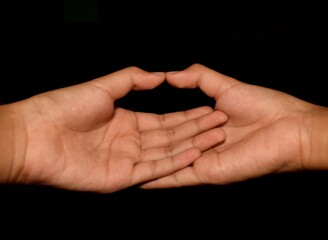 Hands in Dhyani Mudra. Close up shot of pair of human hands with palms resting in lap and thumbs facing each other used in meditation. isolated on a black background.