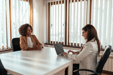 Two businesswoman sitting at the office and discussing
