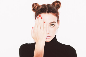 Pretty woman with pigtails covering eye with hand.